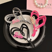 three barbie hair clips on a plate with pearls