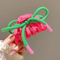 a person holding a pink and green hair bow