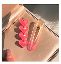 two pink heart shaped hair clips in a box