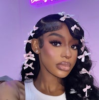 a black woman with long wavy hair and pink bows