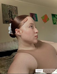 a woman laying on a bed with her hair in a bun