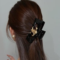 a woman wearing a black and gold hair clip