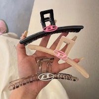 a person holding a pink and black hair clip